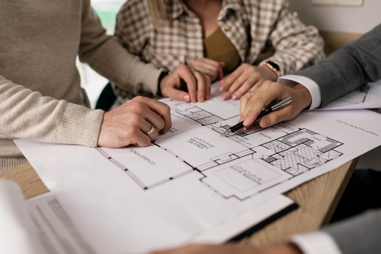 Group examining house floor plans with a real estate agent, highlighting home buying process.